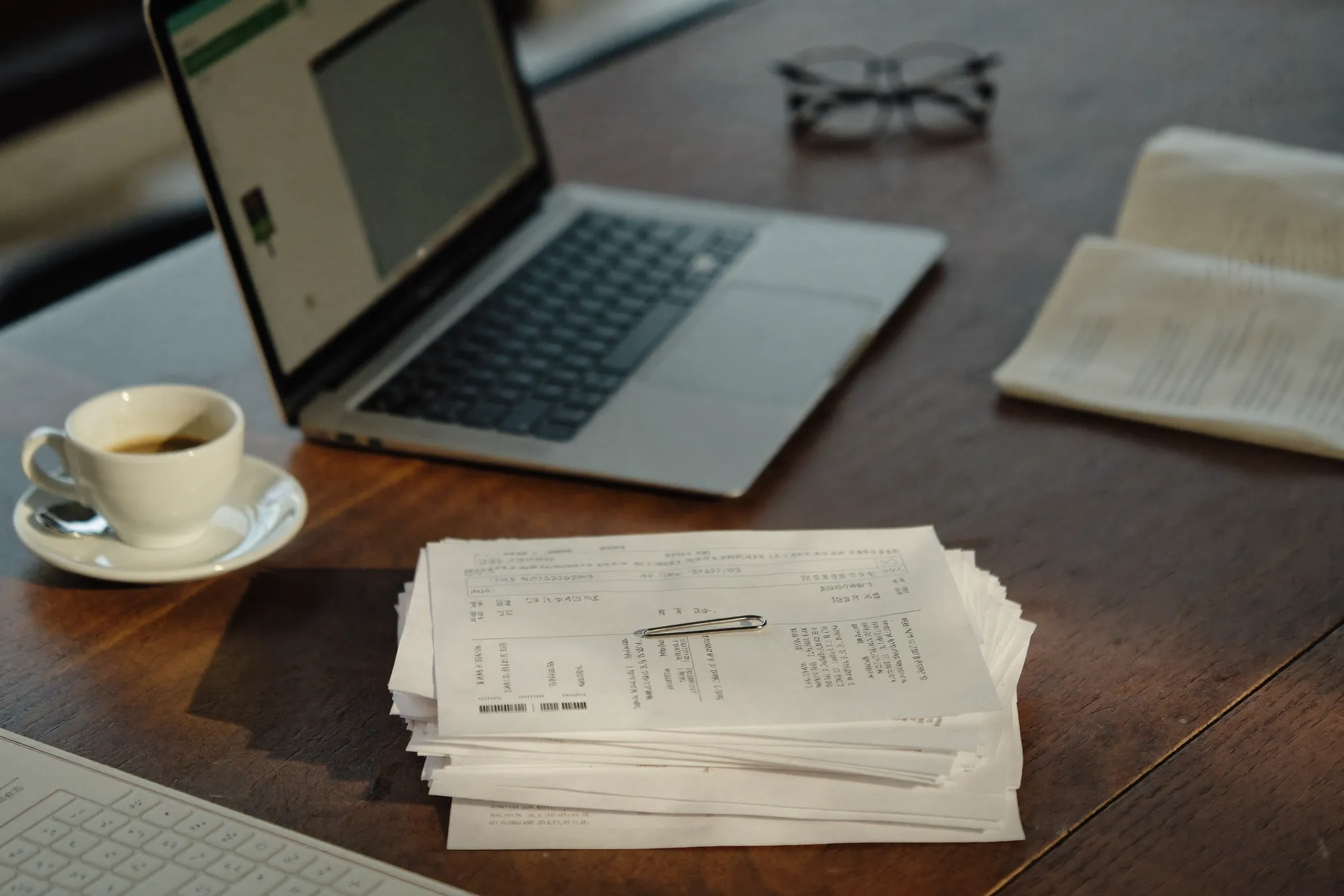 Un bureau rangé : factures classées, ordinateur, café